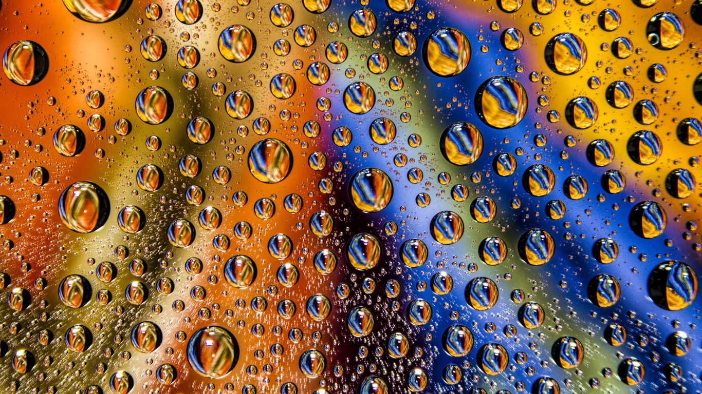 Капли воды на разноцветном стеклянном фоне