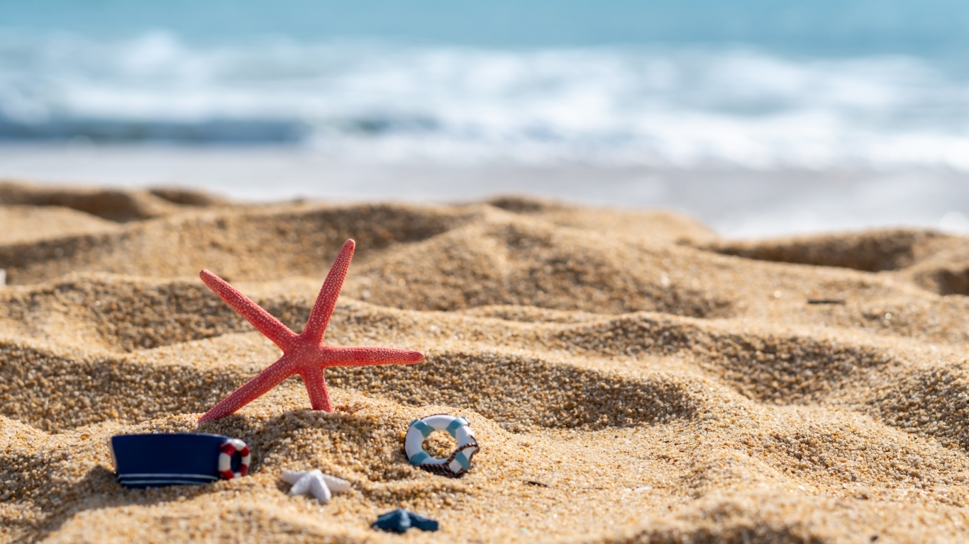 Красная морская звезда и игрушки на песке у моря летом