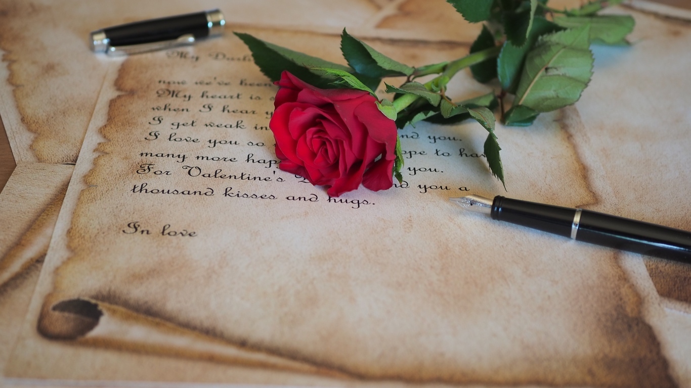 Красная роза с запиской и ручкой на столе