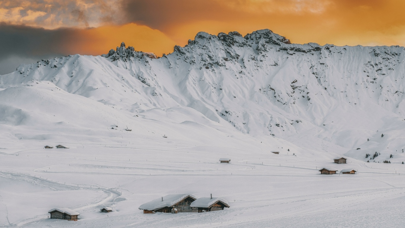 Красивая заснеженная гора под оранжевым небом