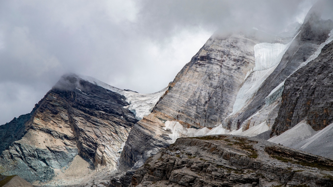 Высокие каменные горы в белых облаках