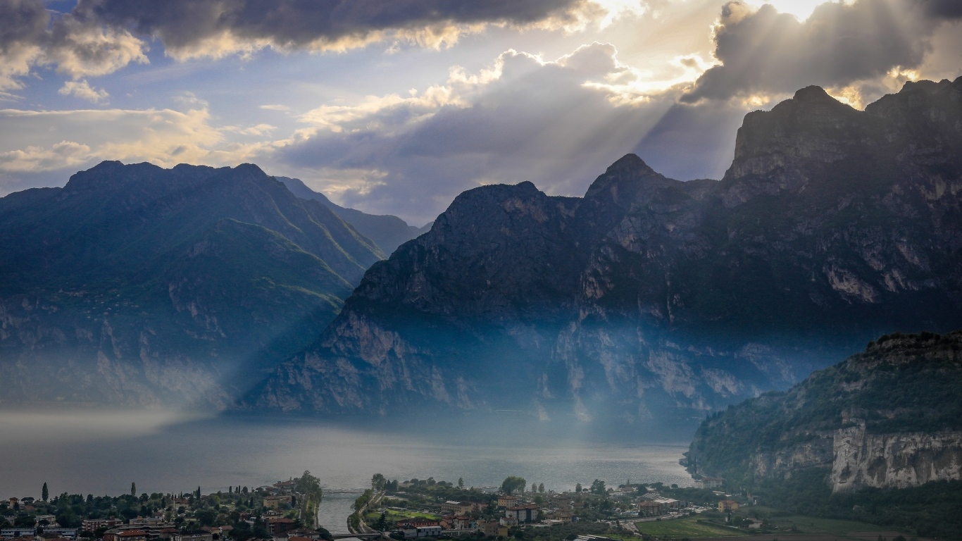 Лучи солнца покрывают горы и город 