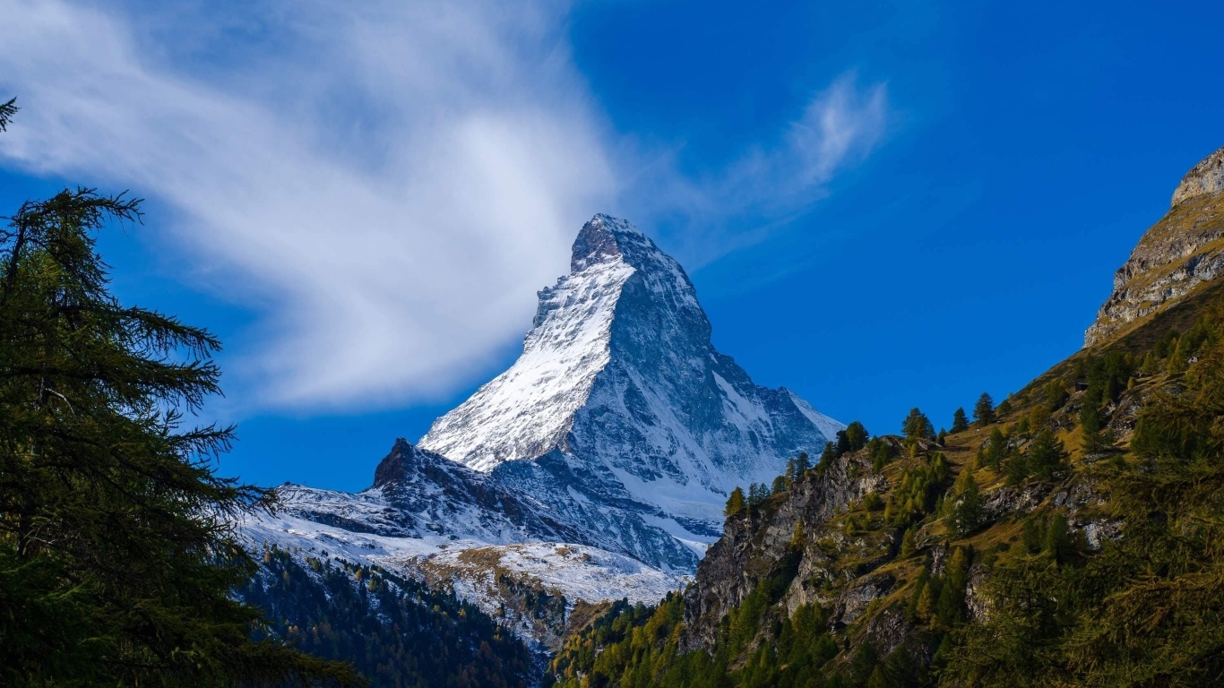 Вид на высокую заснеженную гору под голубым небом
