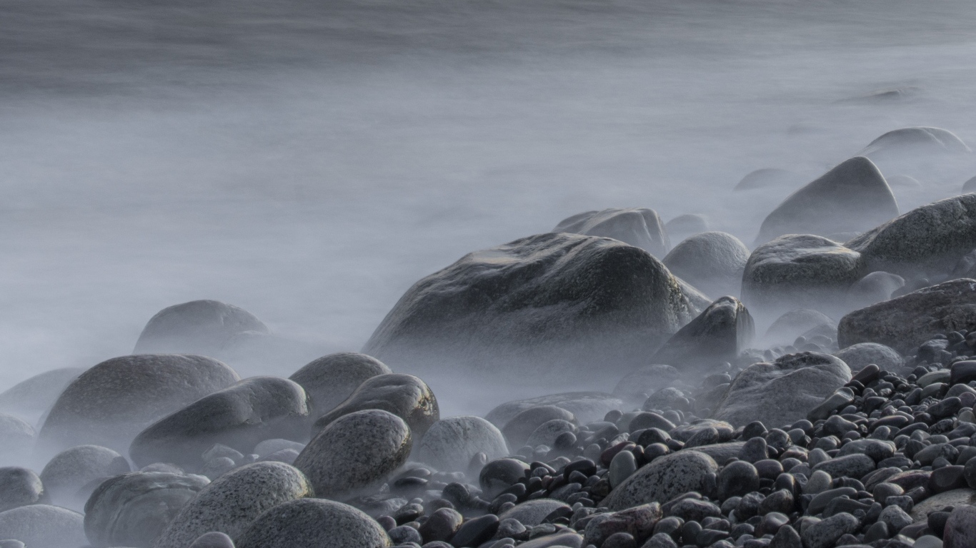 Большие черные камни на берегу моря в тумане