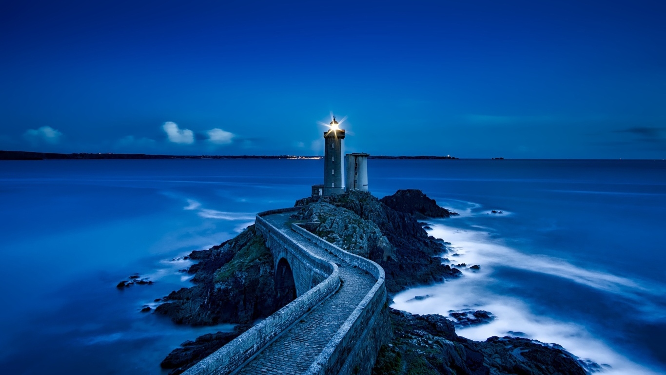 Зажженный маяк на берегу моря ночью