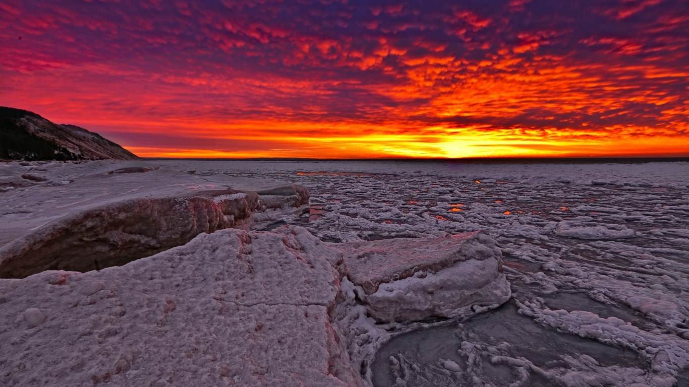 Красный закат солнца покрывает заледеневшее озеро 