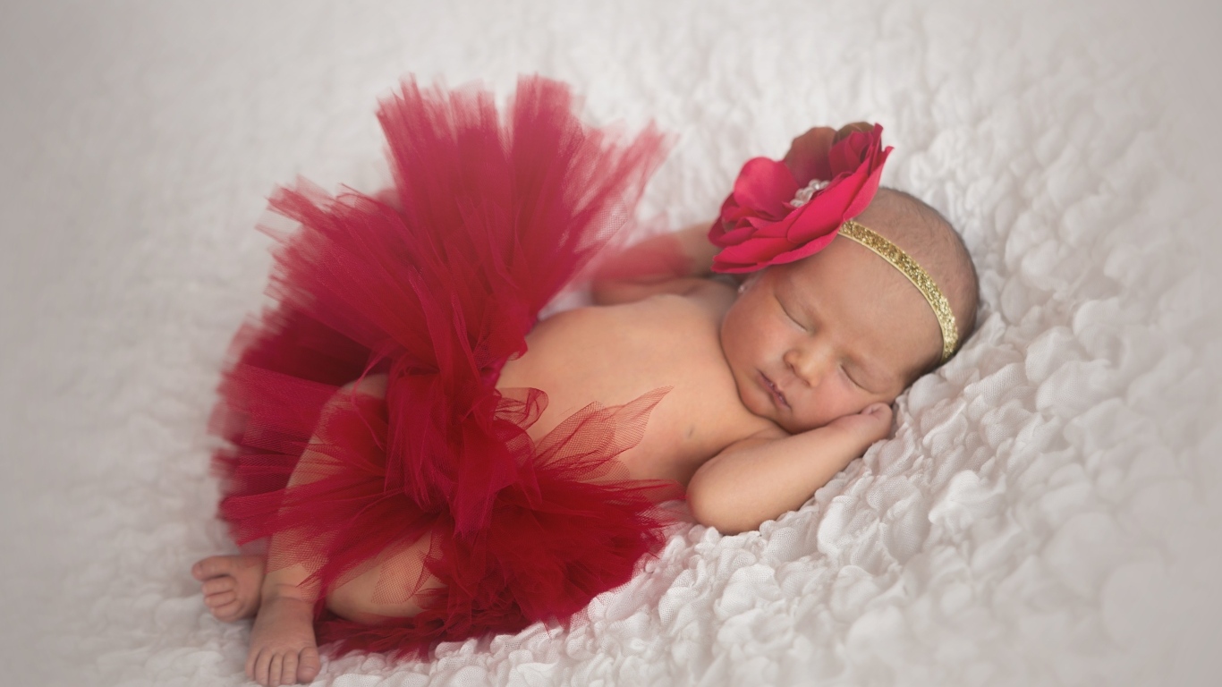 Красивая пышная красная юбка и бант на спящей малышке