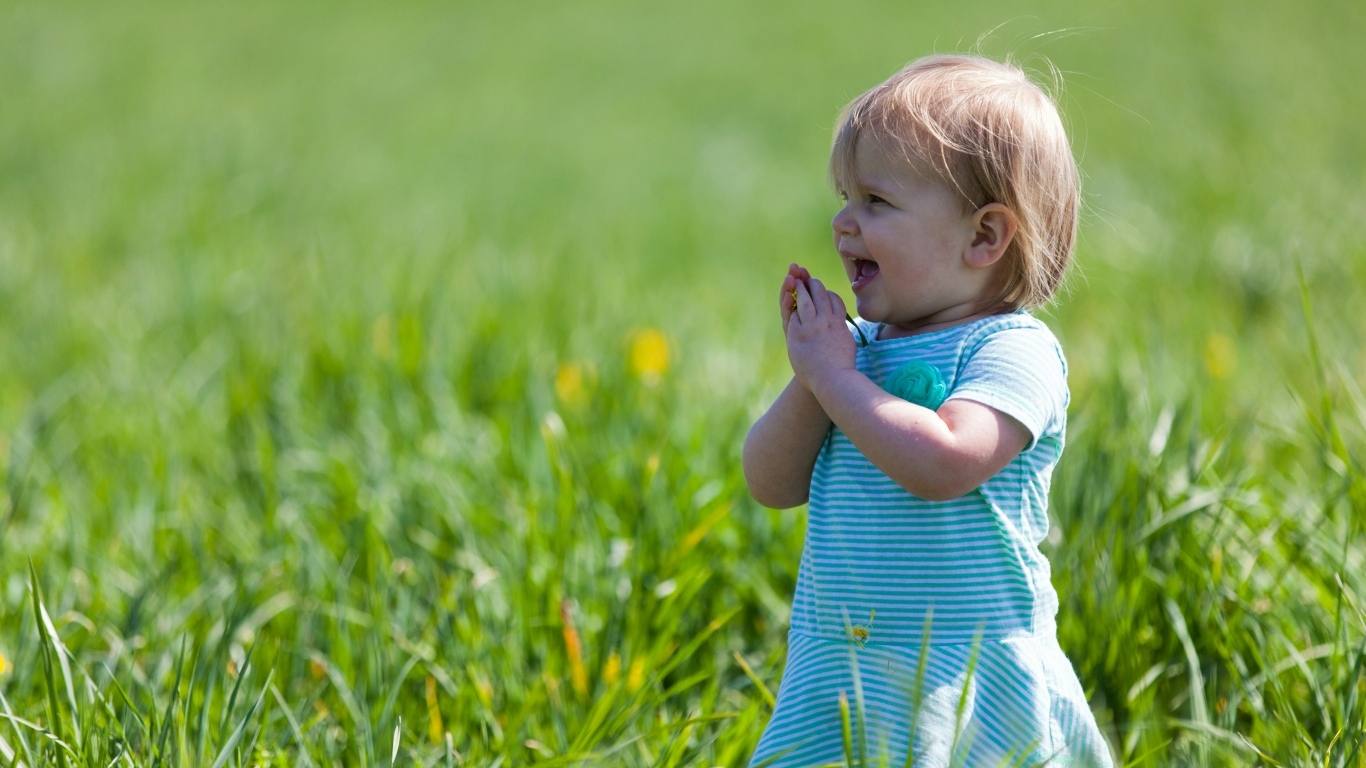 Веселая девочка на поле с зеленой травой