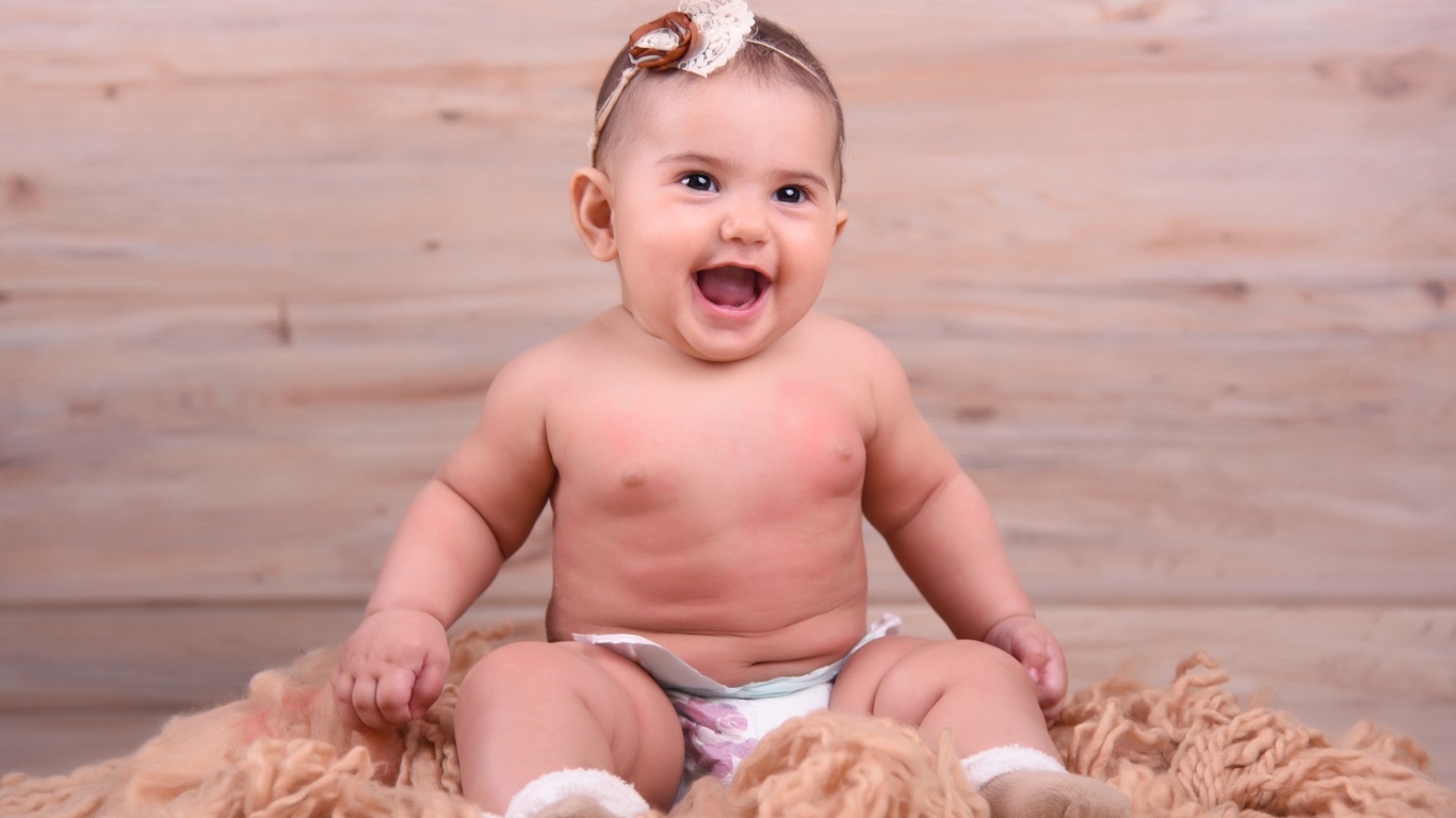 Милый улыбающийся ребенок на фоне деревянной стены