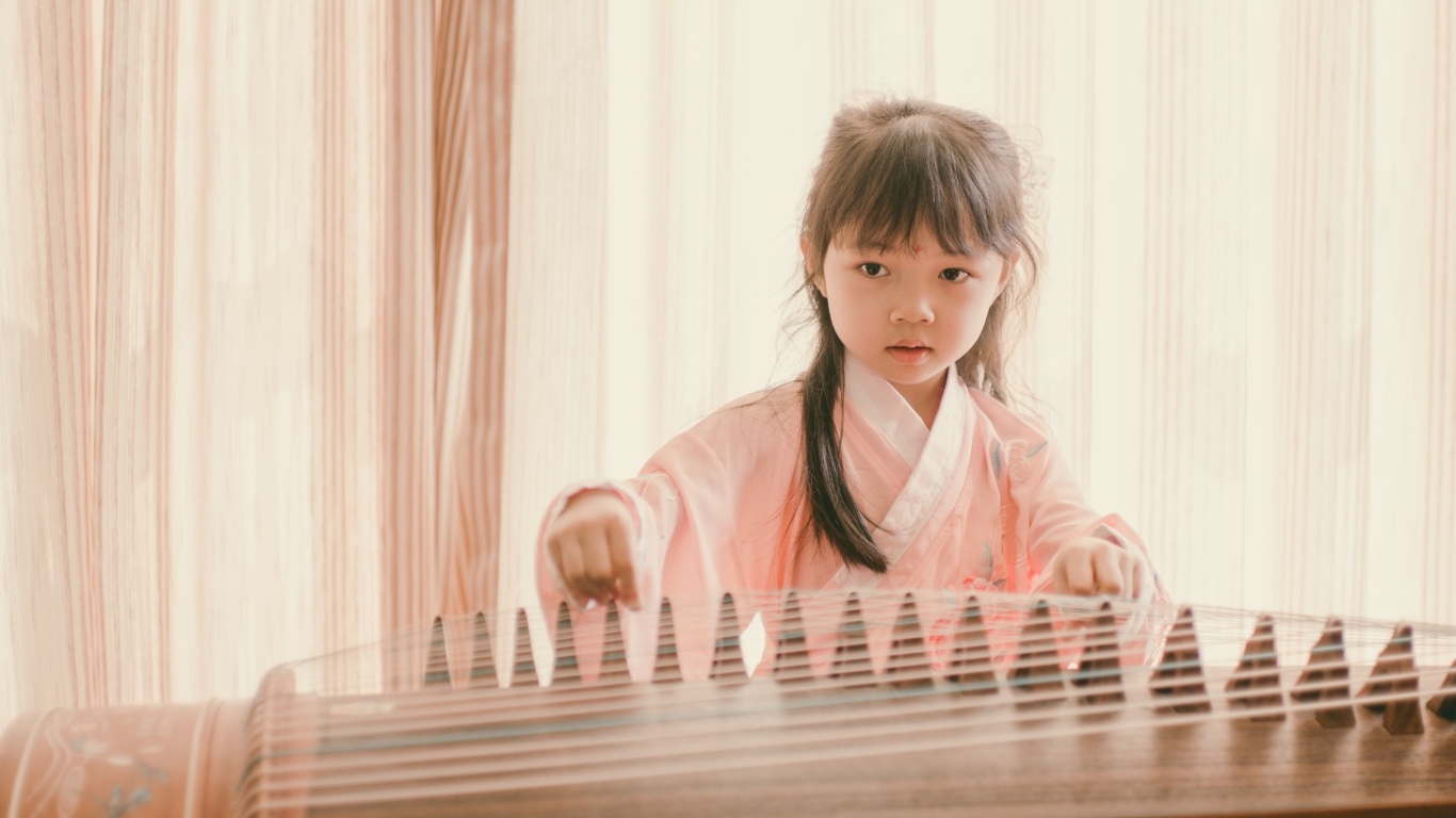 Маленькая девочка азиатка играет на музыкальном инструменте