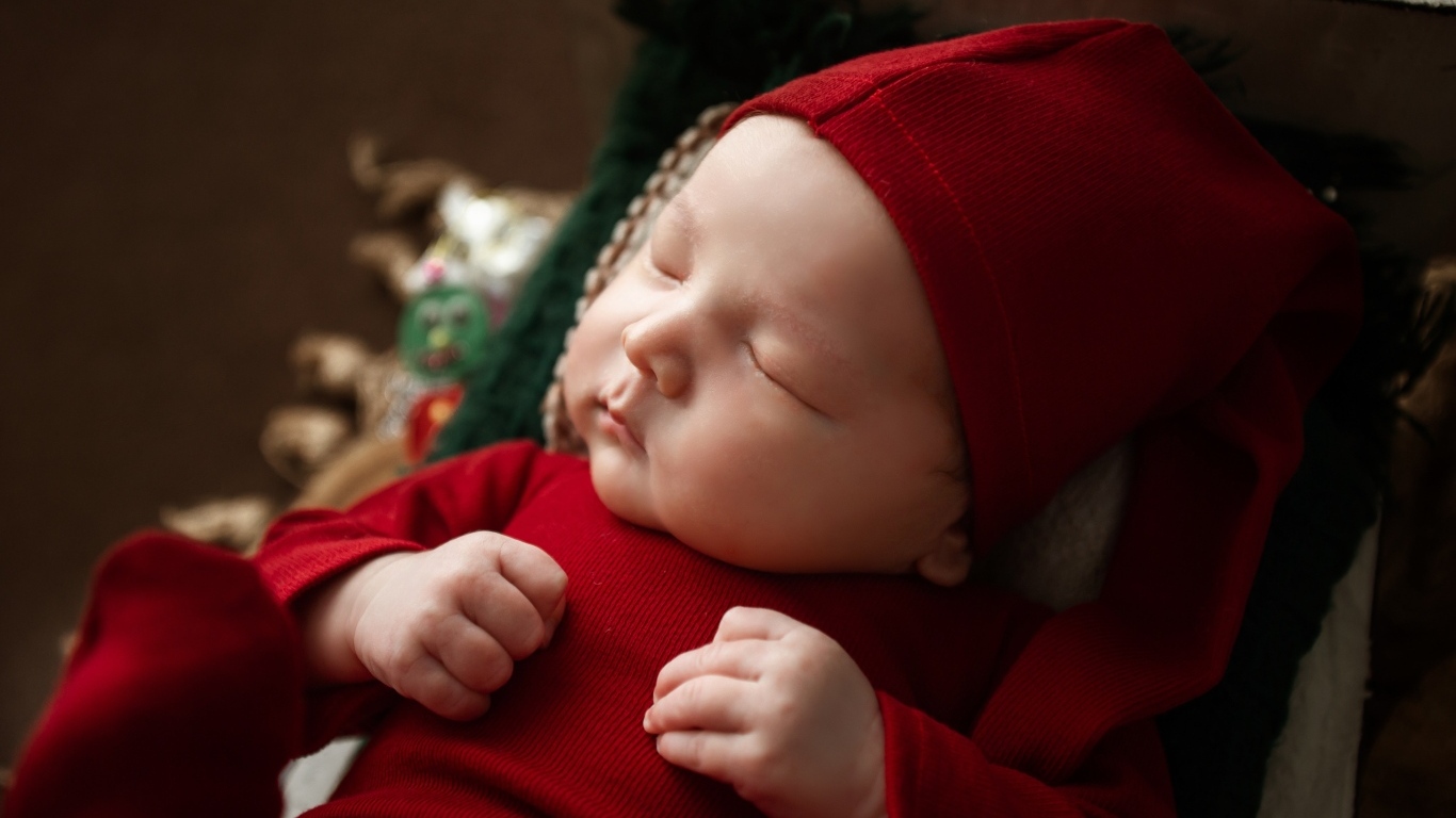 Маленький ребенок спит в красном костюме