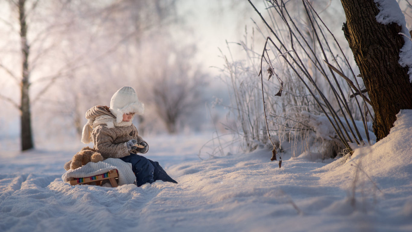 Маленький ребенок на санках в зимнем лесу 