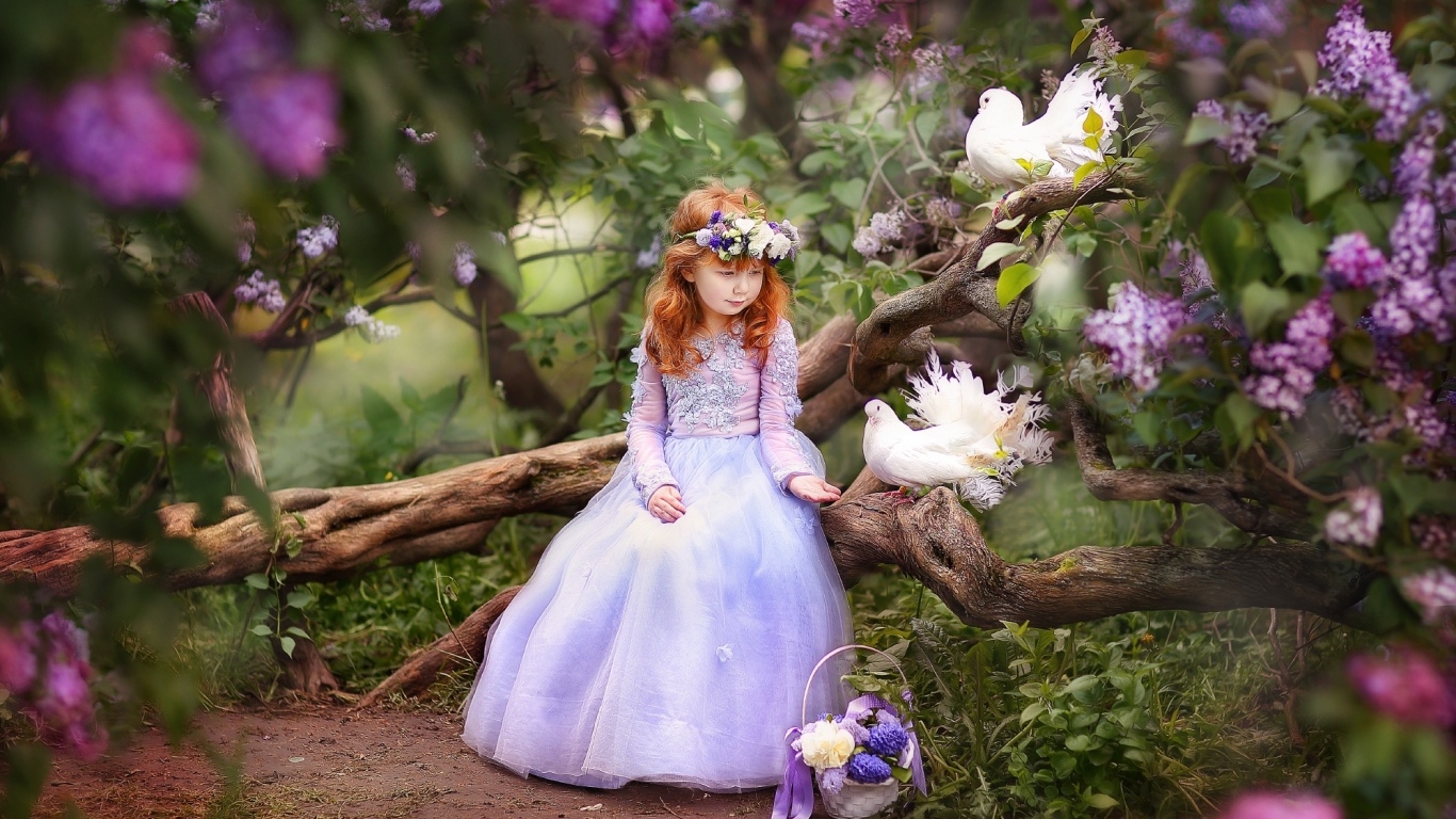 Маленькая девочка в красивом платье на дереве с голубями