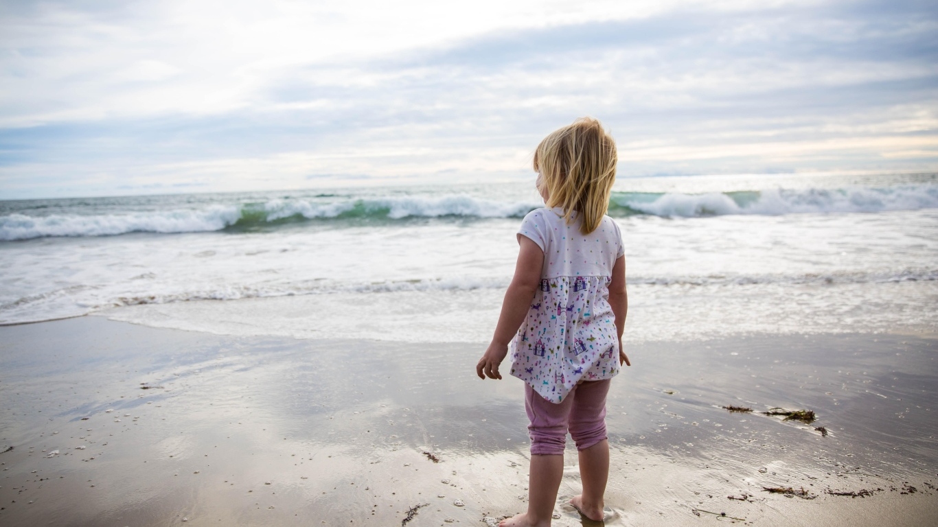 Маленькая девочка стоит на берегу моря