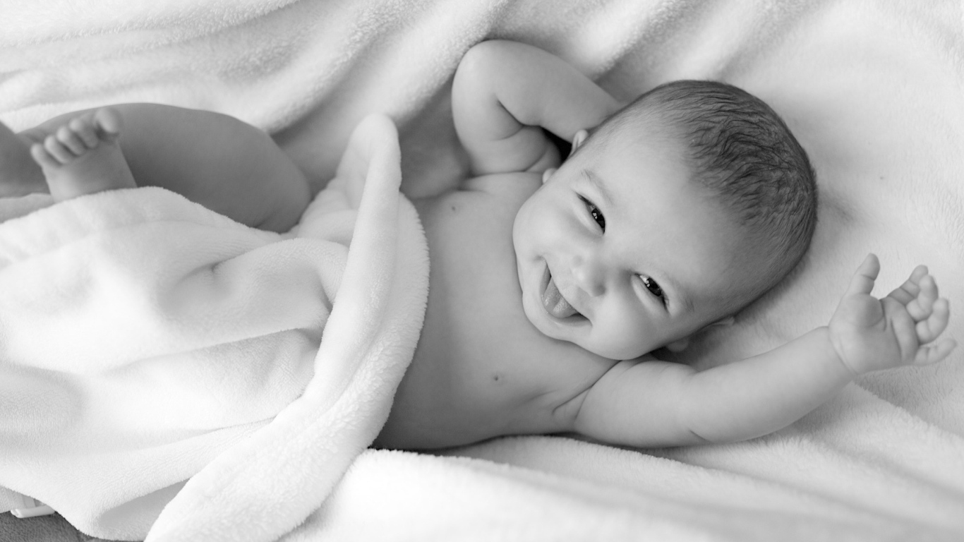 Маленький улыбающийся ребенок в белом покрывале