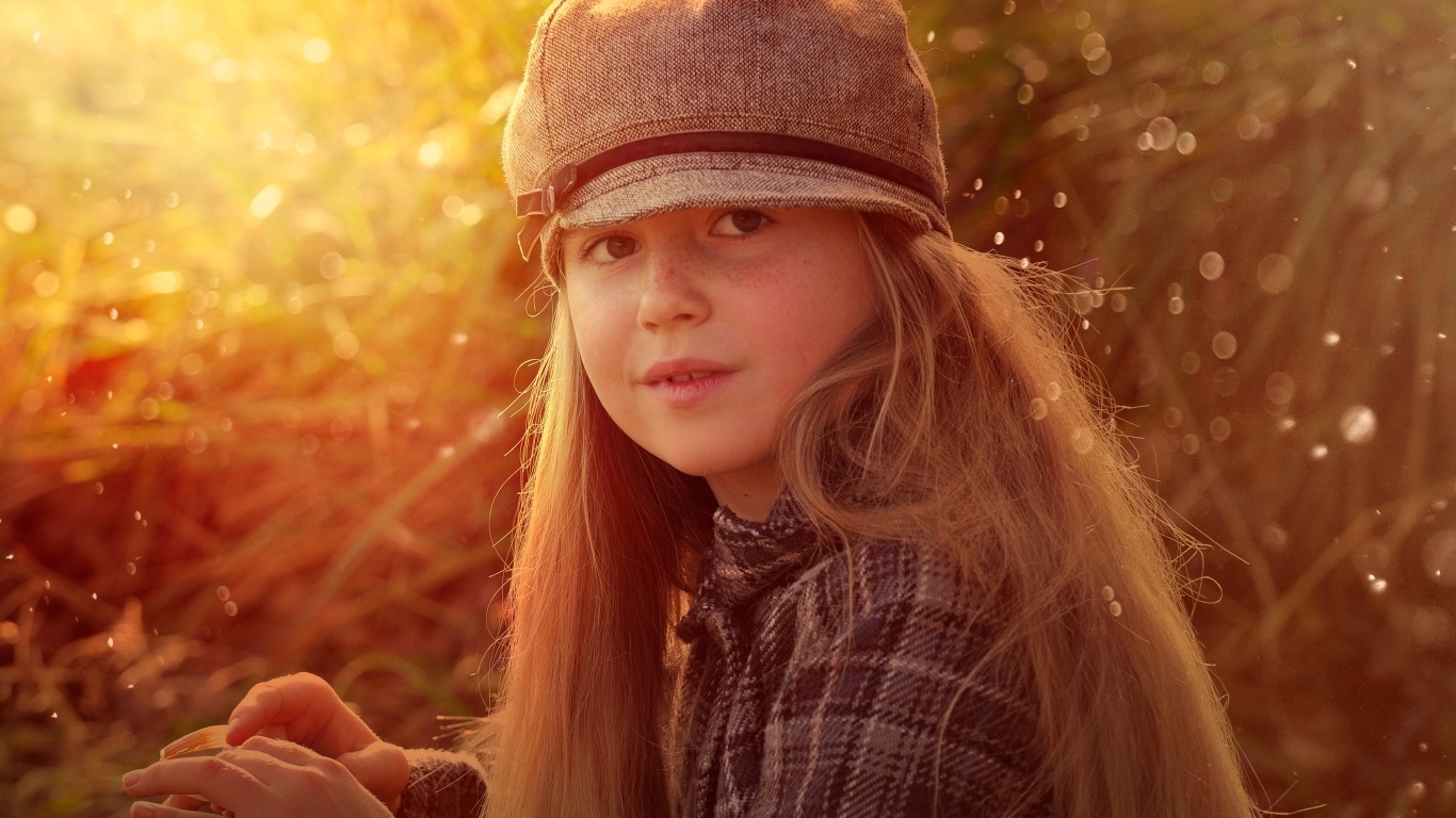 Длинноволосая девочка в кепке в лучах солнца