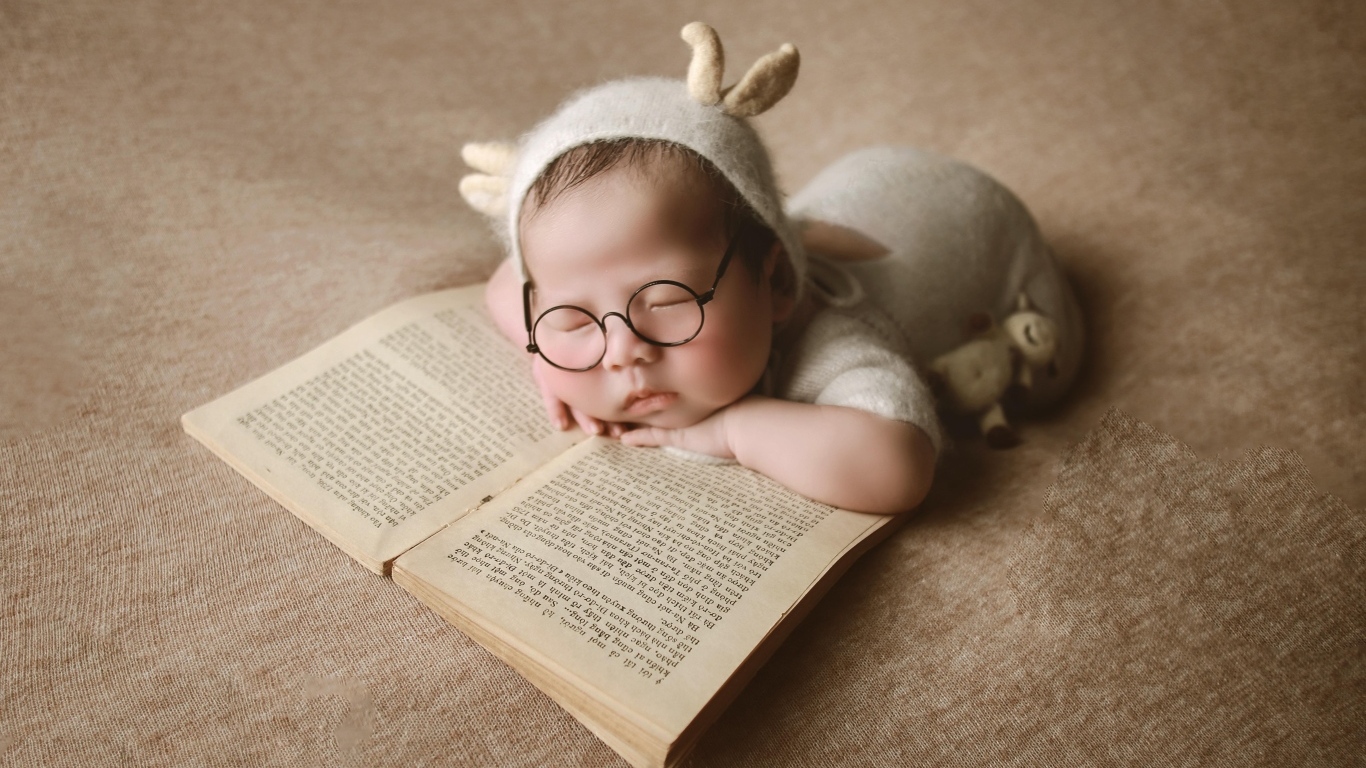 Новорожденный ребенок спит с книгой