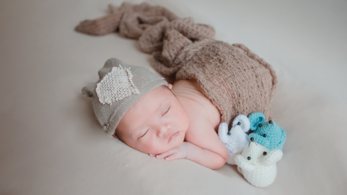 Новорожденный малыш спит на сером покрывале