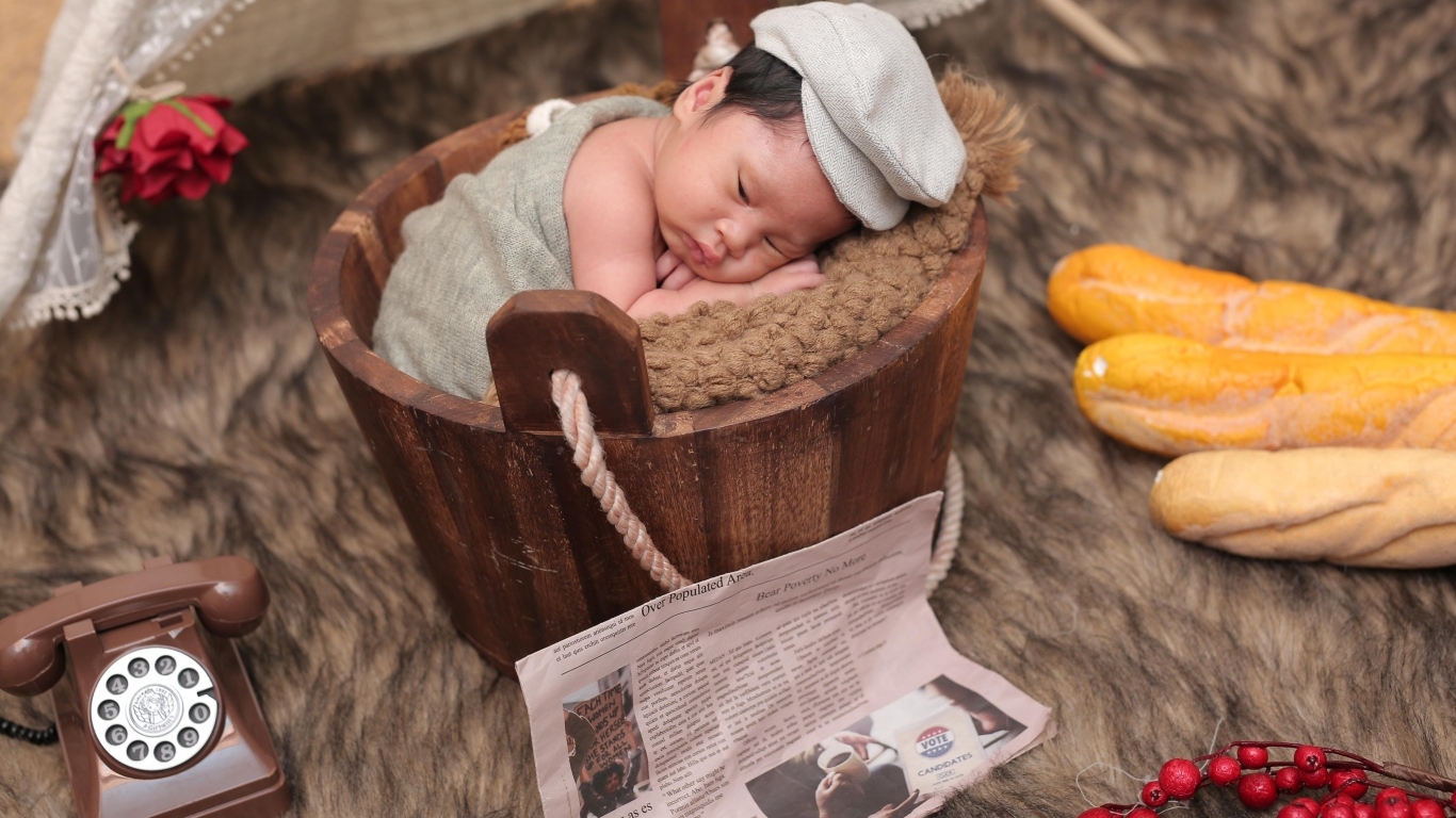 Новорожденный маленький мальчик в деревянном ведре на фотосессии 