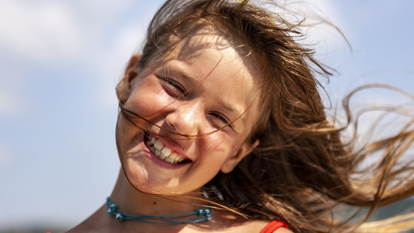 Улыбающаяся маленькая девочка стоит на ветру