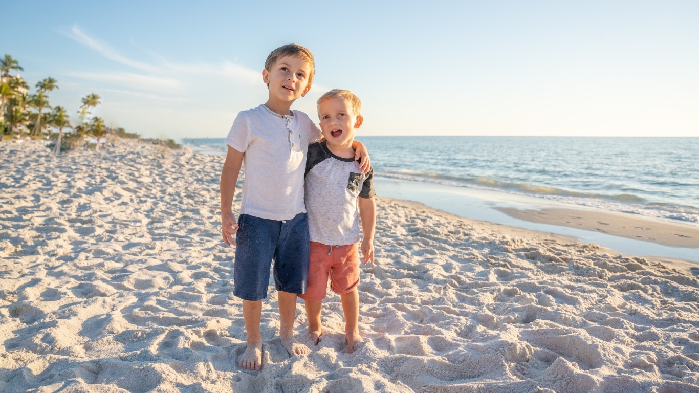 Два маленьких мальчика стоят на песке у моря