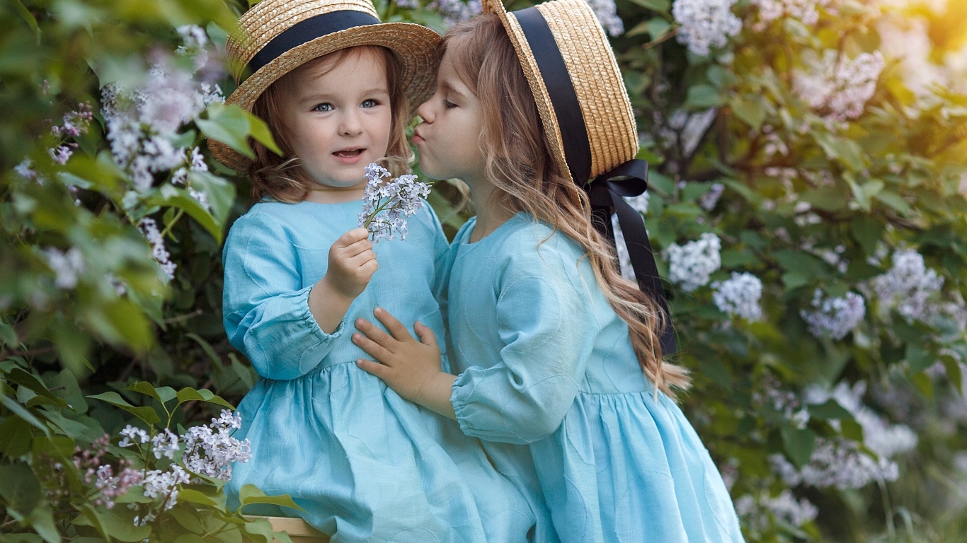 Две маленькие девочки в саду с сиренью