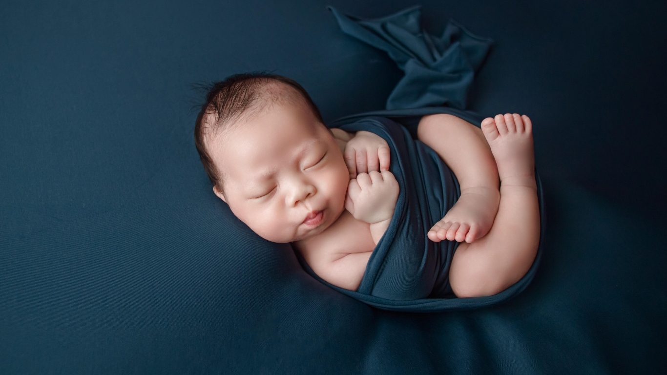 Новорожденный малыш в черном покрывале