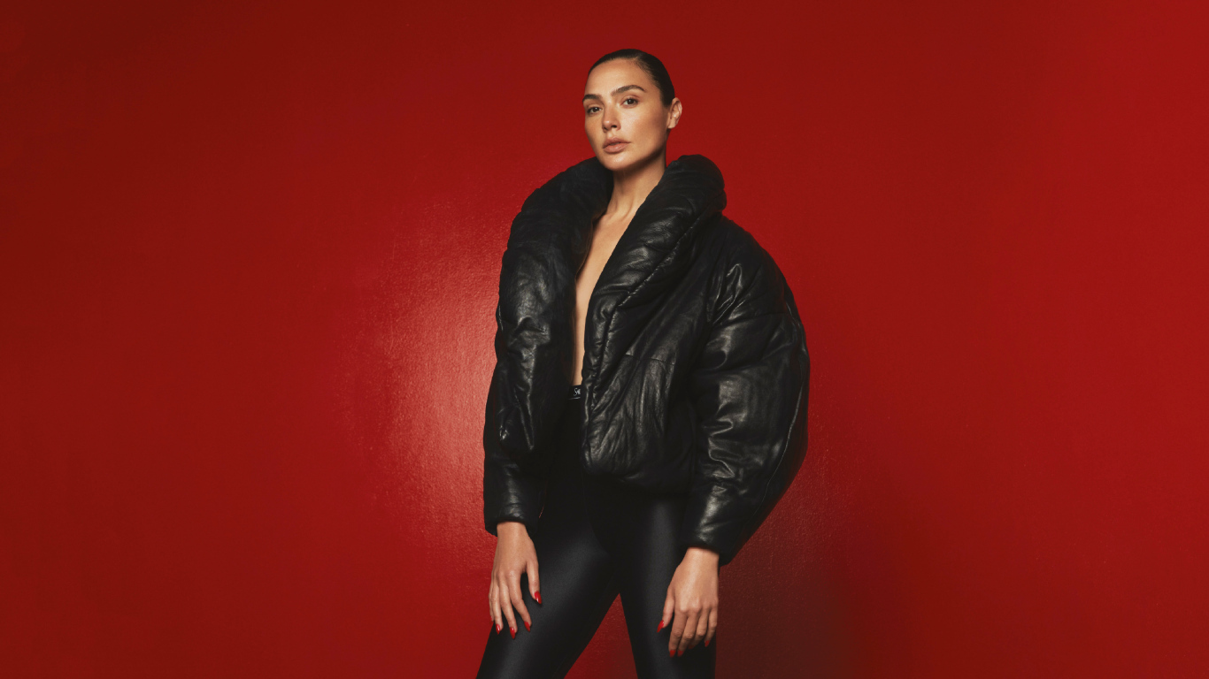 Актриса Галь Гадот в черной куртке на красном фоне