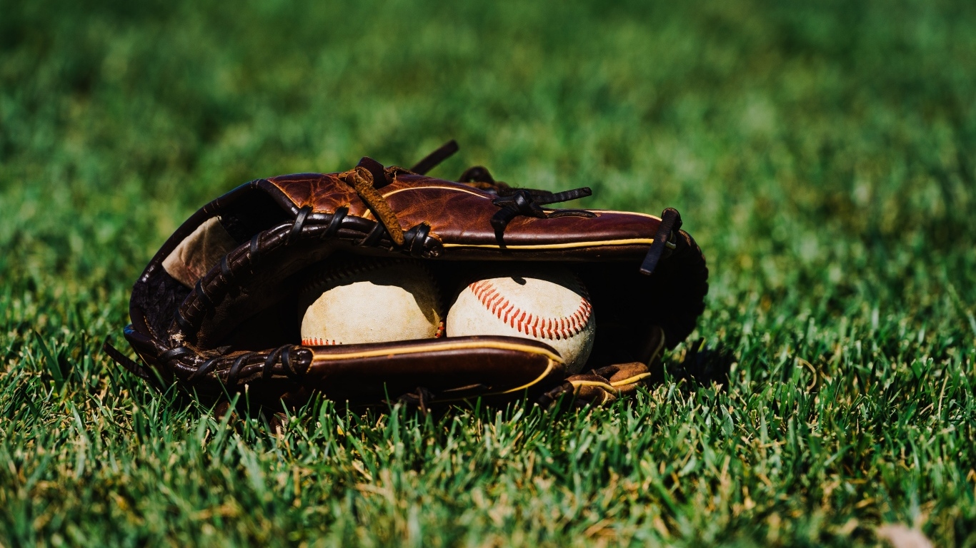Бейсбольная перчатка и мячи на зеленой траве