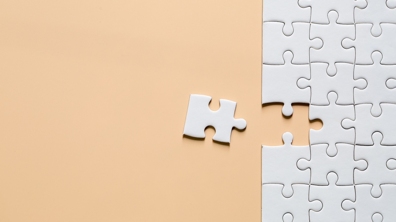 Белый пазл собирают на бежевом фоне