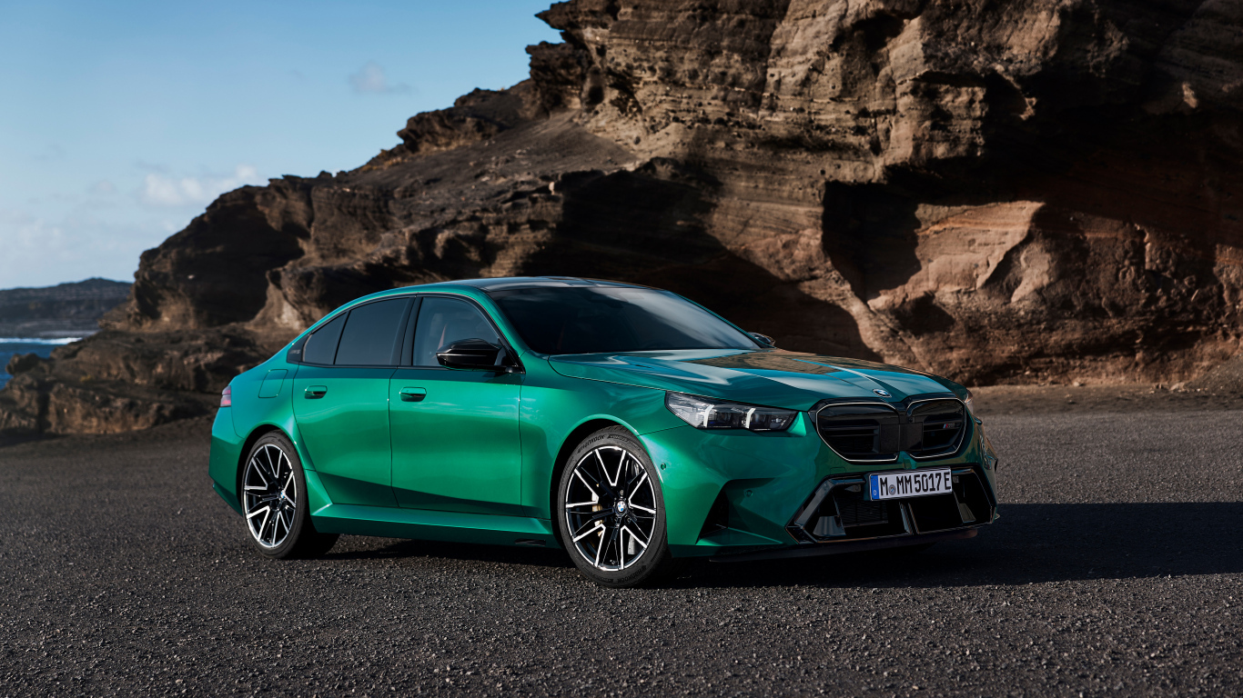 Зеленый автомобиль BMW M5 2024 года на фоне гор