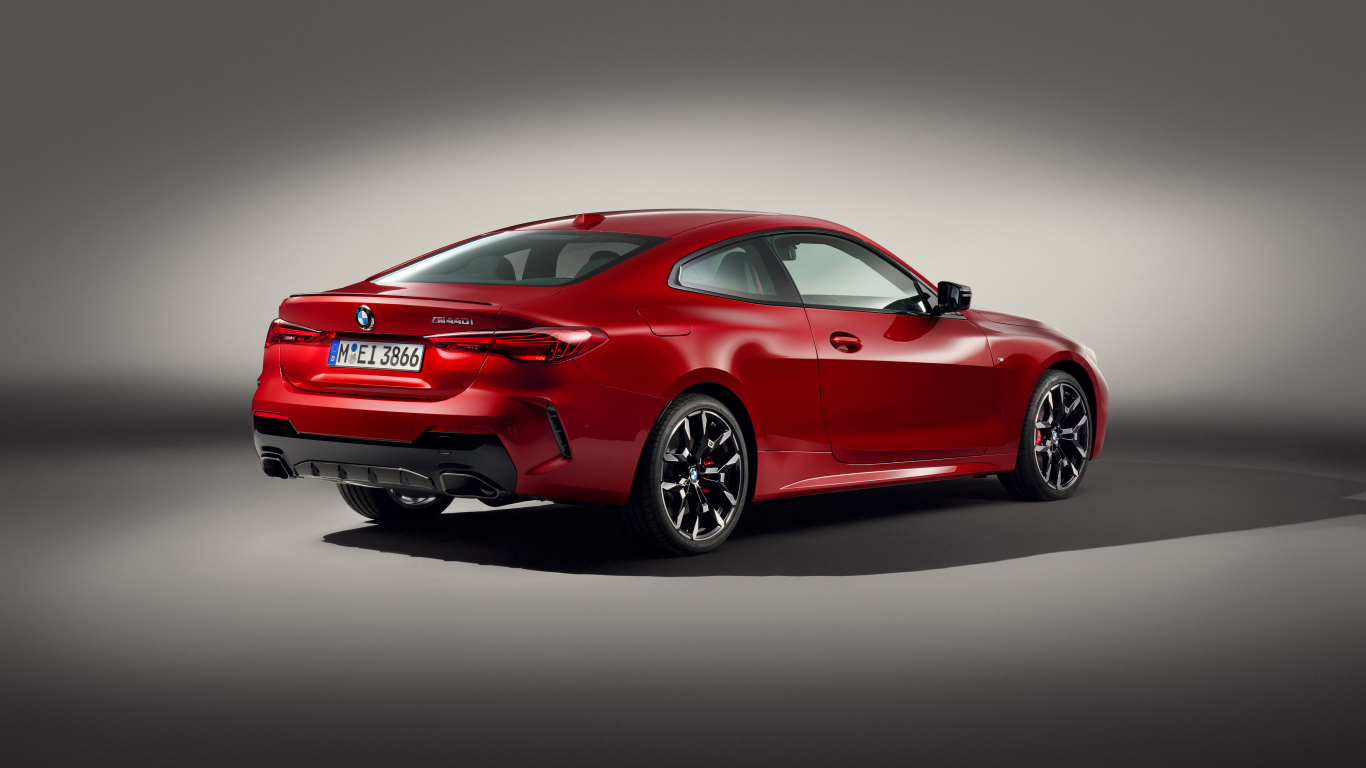 Красный автомобиль BMW M440i XDrive Coupé 2024 года на сером фоне