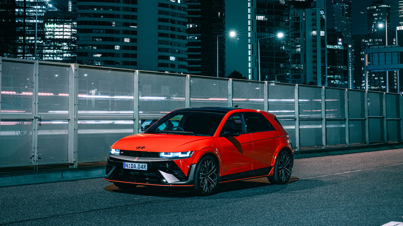 Красный автомобиль Hyundai IONIQ 5 N 2024 года у забора