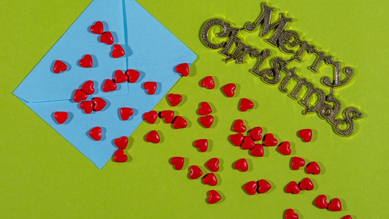 Красные сердечки и голубой конверт на зеленом фоне на Рождество