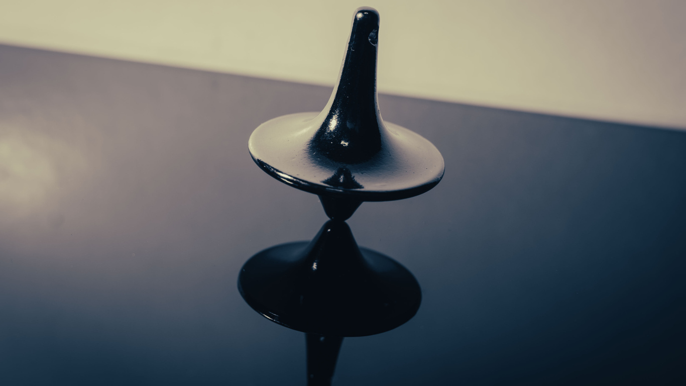 Черный волчок на ровной поверхности