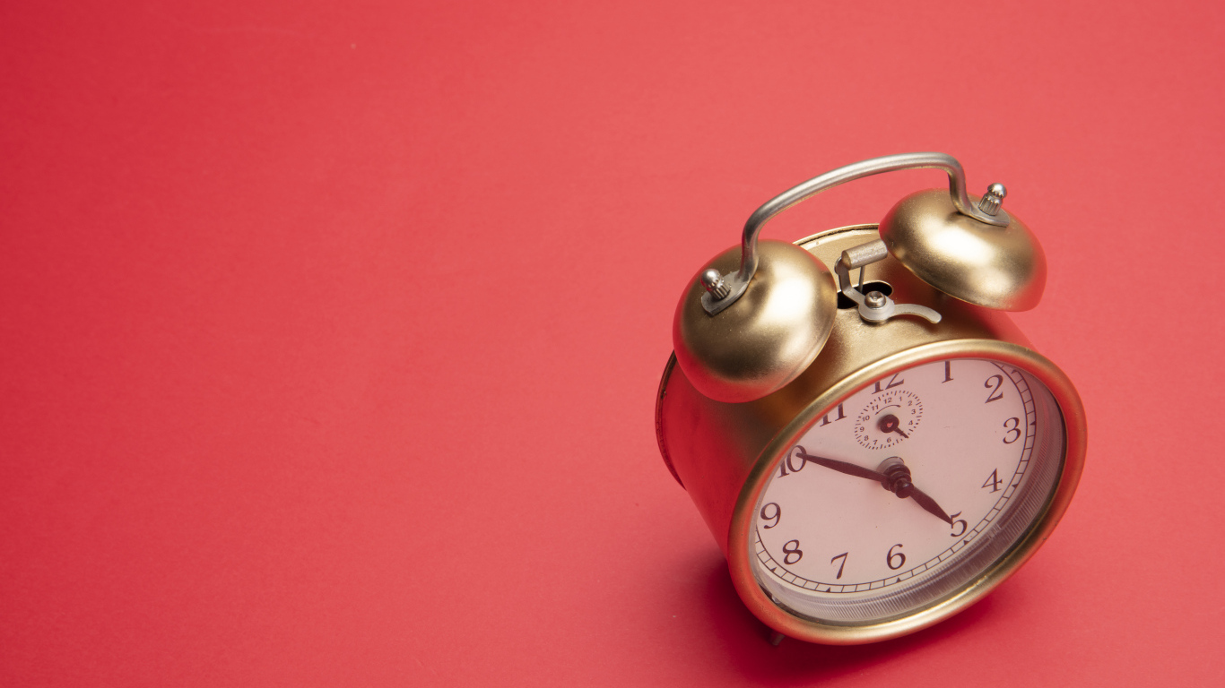 Золотой будильник на красном фоне