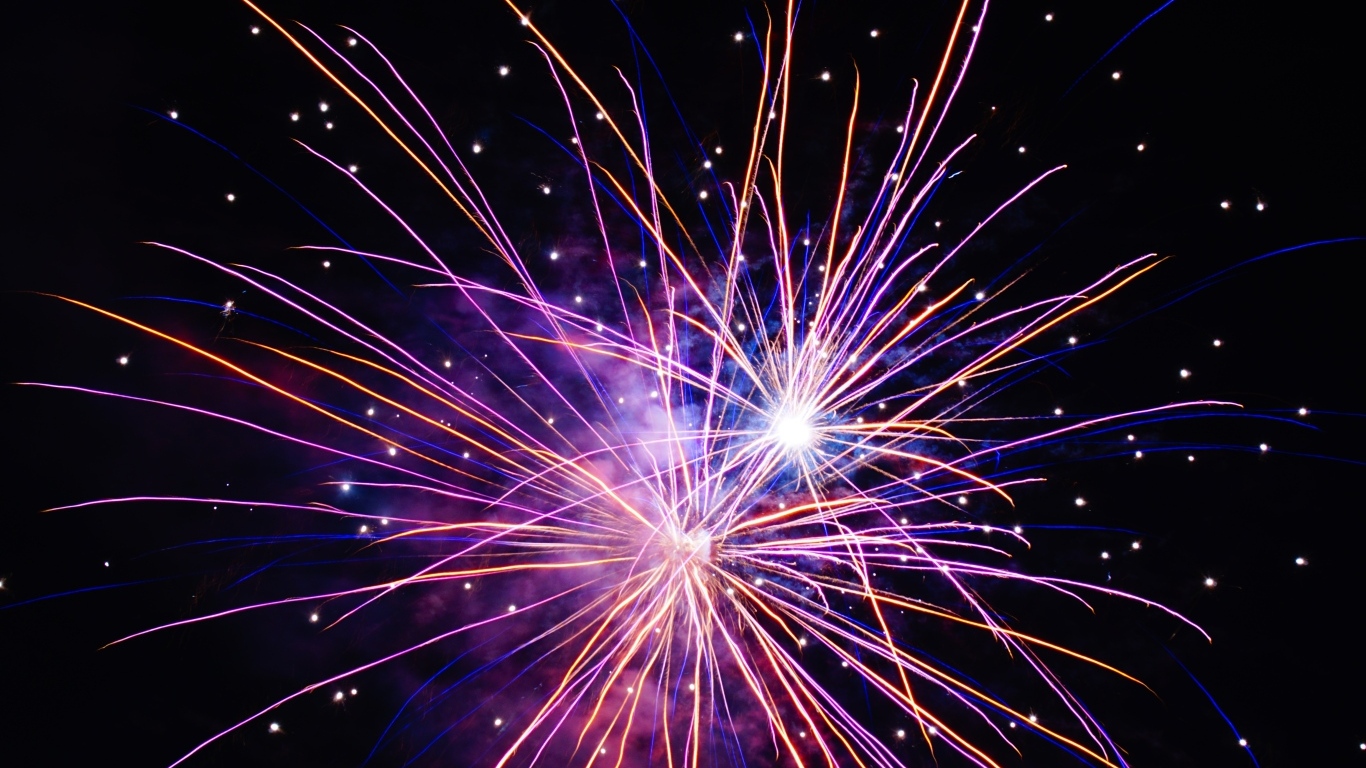 Разноцветные сиреневые искры фейерверка на черном фоне