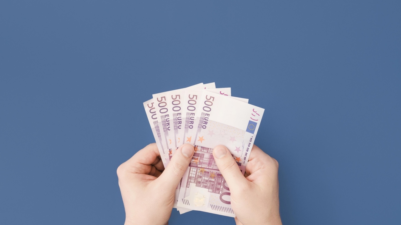 Купюры в пятьсот евро в руках на синем фоне