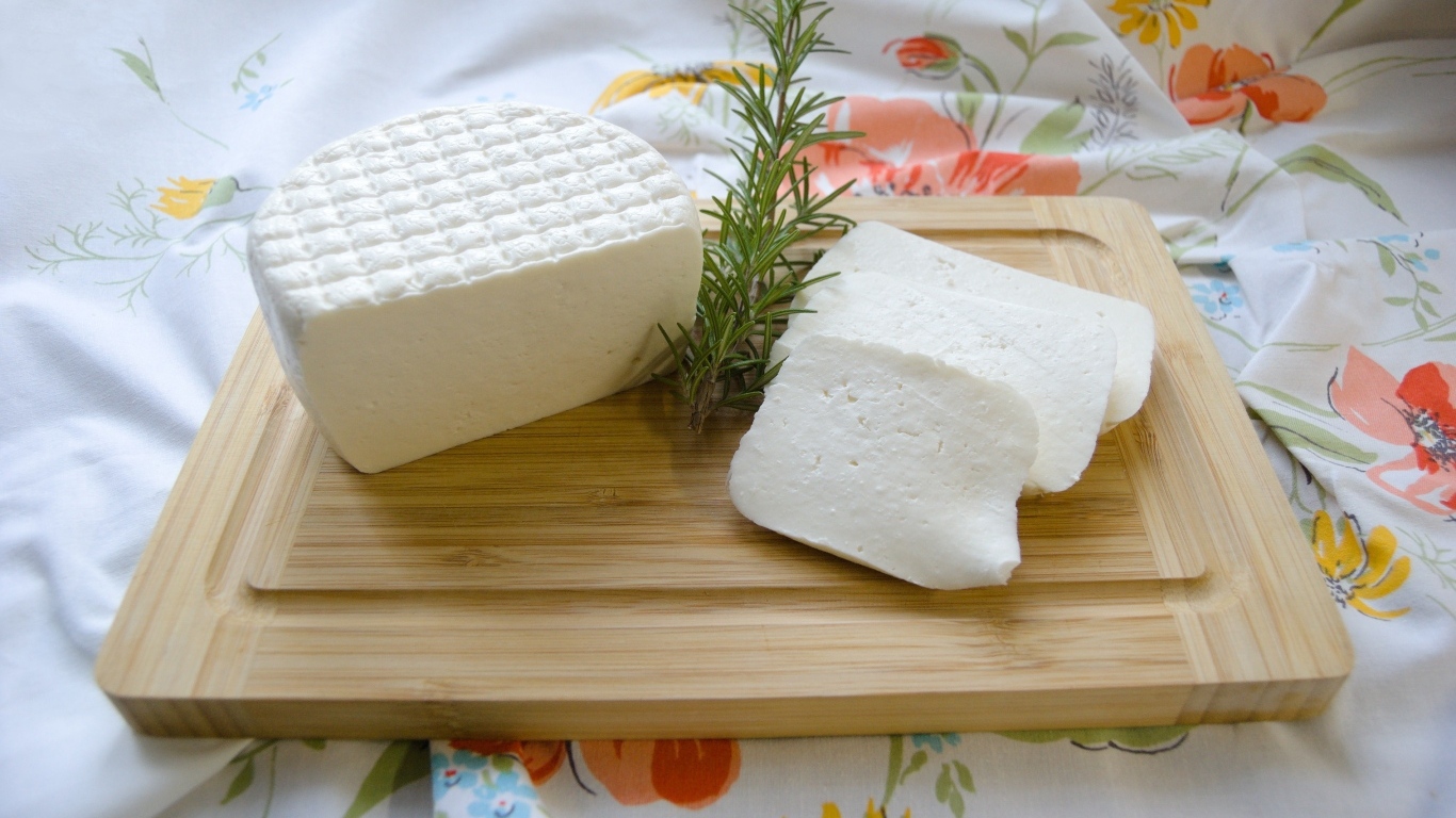 Кусок сыра с розмарином на разделочной доске