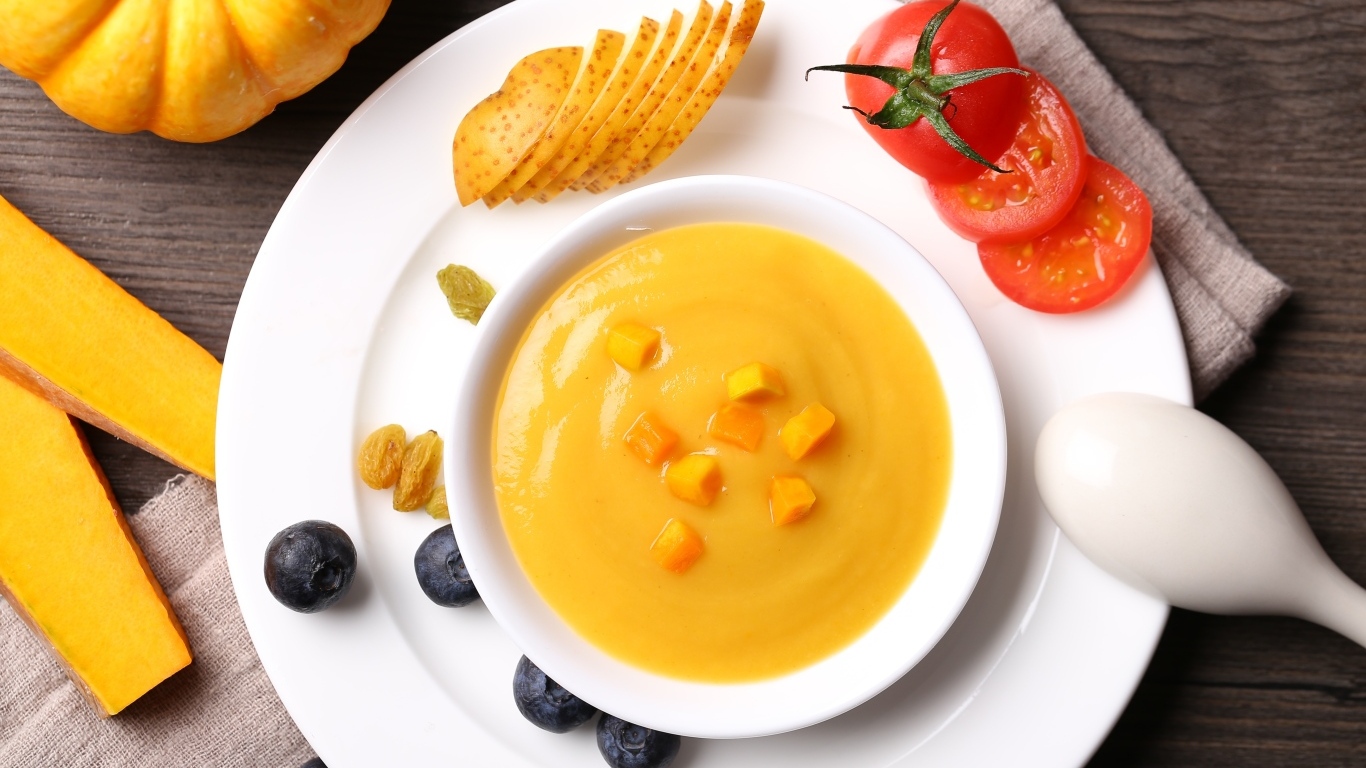 Тыквенный суп пюре на тарелке с картофелем и помидором