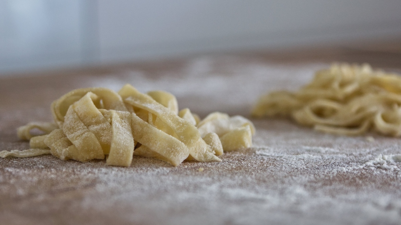 Сырое тесто для лапши на покрытом мукой столе