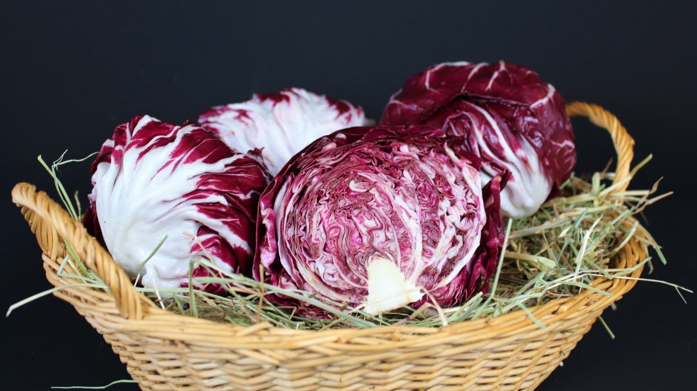 Красная капуста в корзине на черном фоне