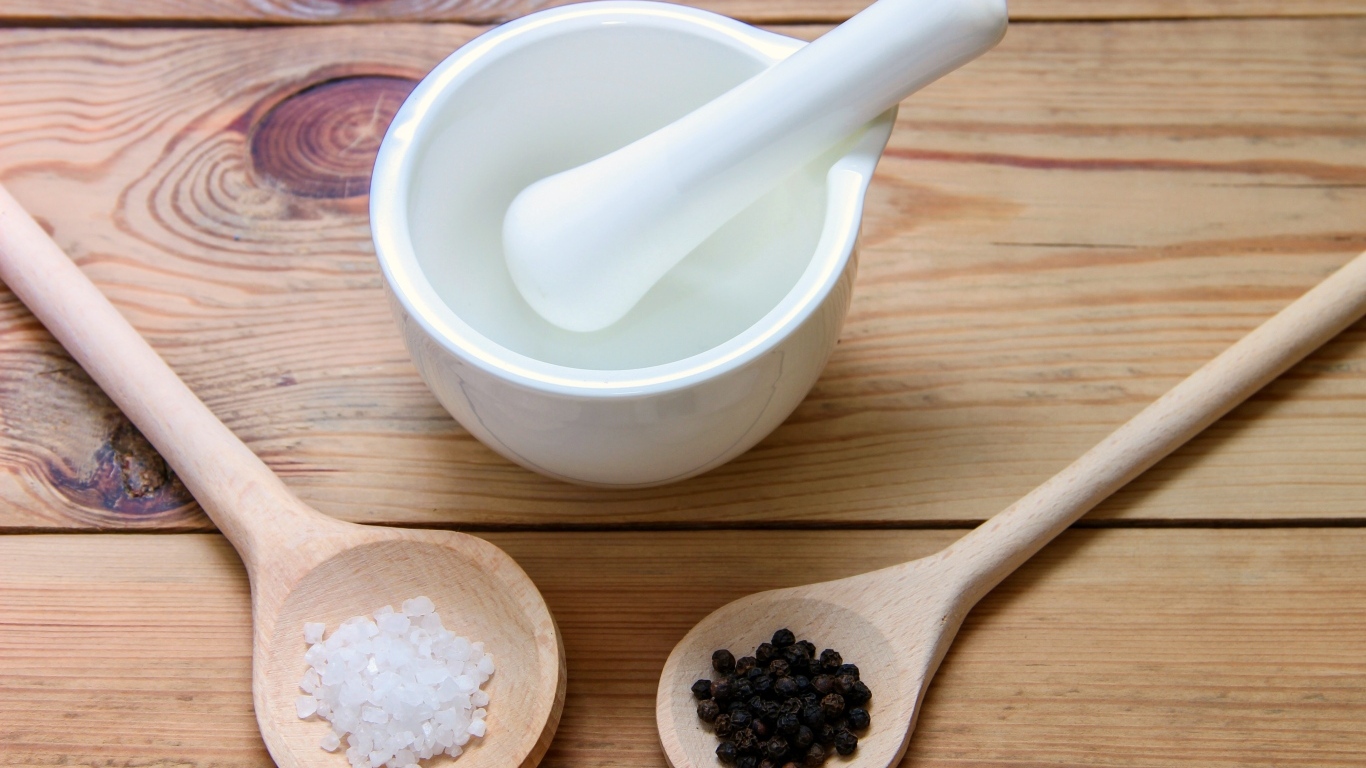 Соль с перцем на столе с деревянной ступкой