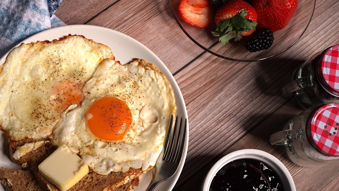 Яичница с гренками на столе с клубникой