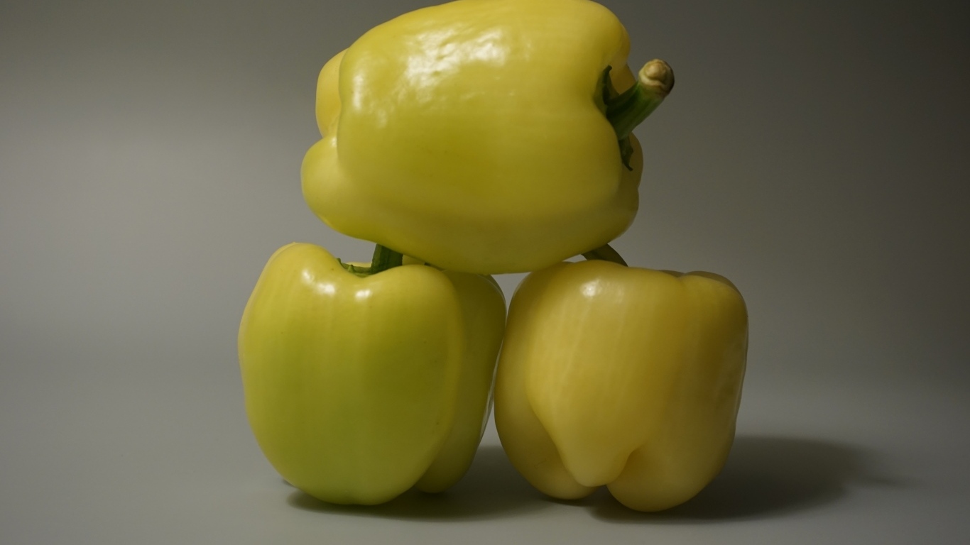 Три желтых перца на сером фоне