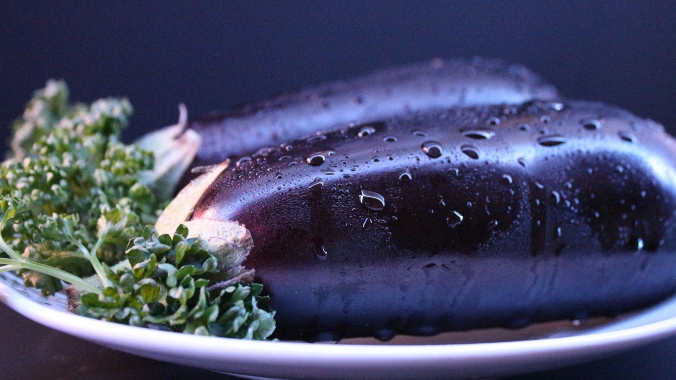 Два баклажана на тарелке с зеленью