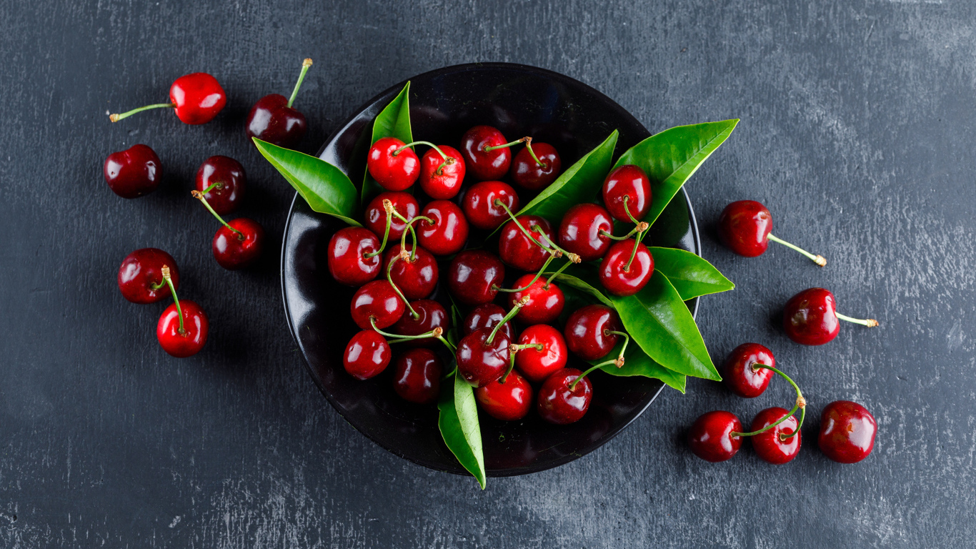 Черная  тарелка с красными ягодами черешни