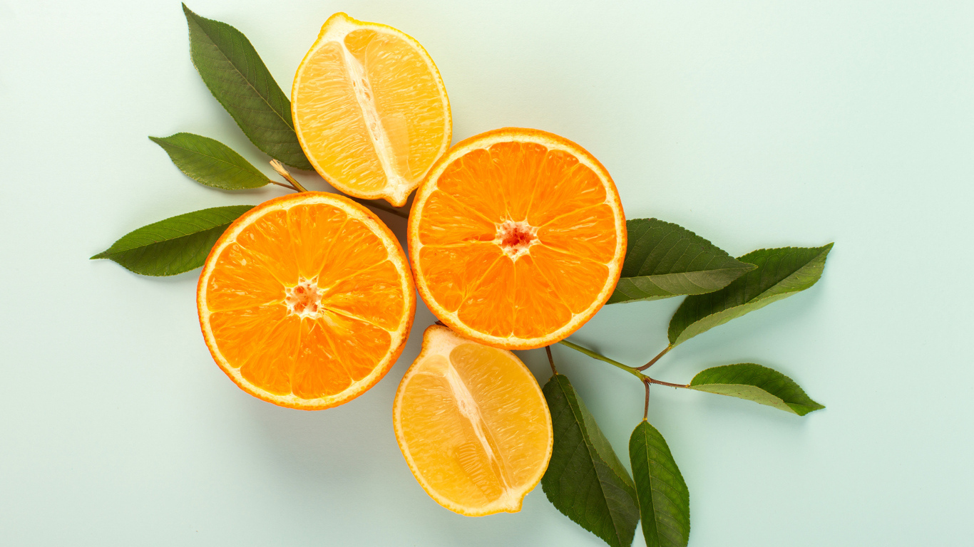 Половинки лимона и апельсина на столе с зелеными листьями