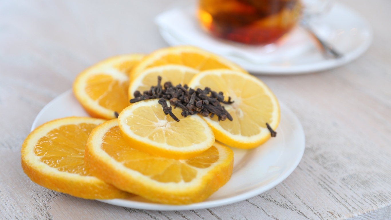 Лимон и апельсин с гвоздикой на тарелке