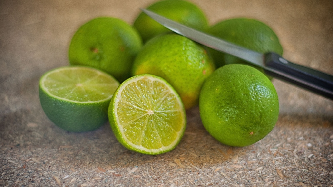 Много зеленых лаймов на столе с ножом